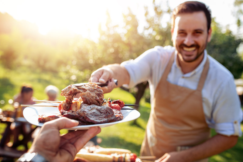 Uomo che serve carne alla griglia